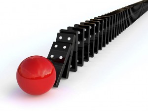 Line of dominoes knocked over by red ball, representing momentum for change
